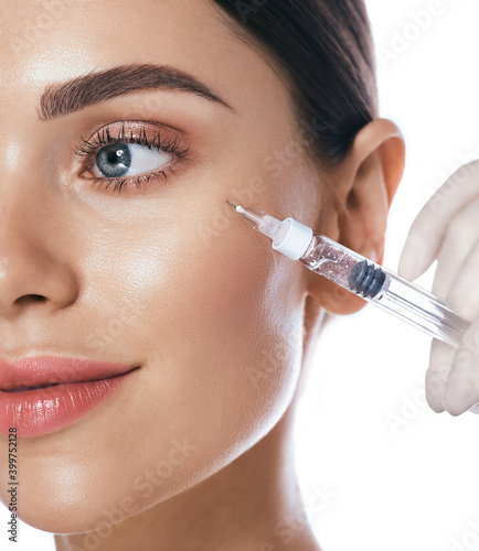 Beautiful woman during facial mesotherapy for smoothing of mimic wrinkles around eyes. Beautician doing anti-aging injection for rejuvenation and lift skin