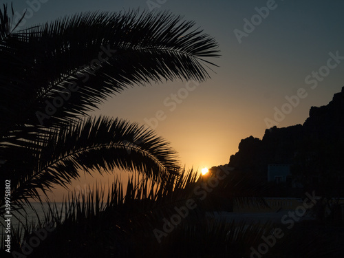 Zachód słońca nad morzem, górami i palmami