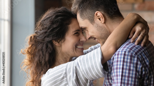 Love in your eyes. Loving millennial woman embracing neck of beloved man with warmth care. Happy wife girlfriend looking in husband boyfriend eyes smiling touching forehead share affectionate feeling