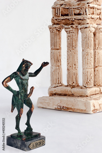An erotic statuette of a naked satyr with another representing a Greek temple nearby.