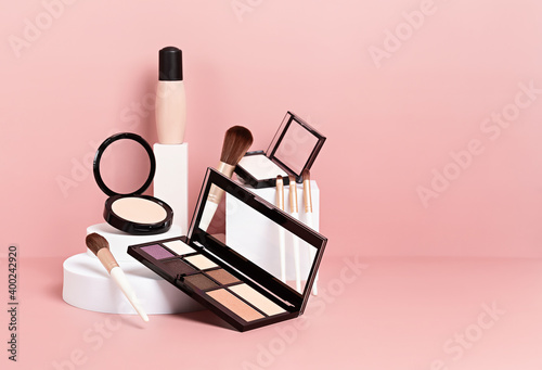 Make up products prsented on white podiums on pink pastel background.