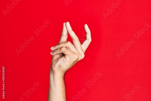 Arm of caucasian white young man over red isolated background snapping fingers for success, easy and click symbol gesture with hand