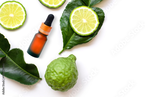 Green Bergamot or kaffir lime fruit with cut in half and bottle of essential bergamot oil extract isolated on white background. Hair tonic concept. Top view. Flat lay.