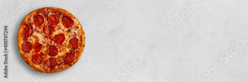 Tasty pizza banner with salame on bright concrete surface with place for your text. Top view of pepperoni sliced pizza. 