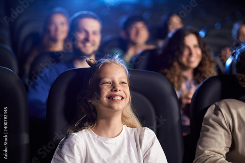 Young teenage girl laughing in movie theater.