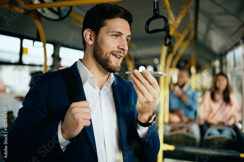 Happy businessman talking over cell phone's speaker in public bus.