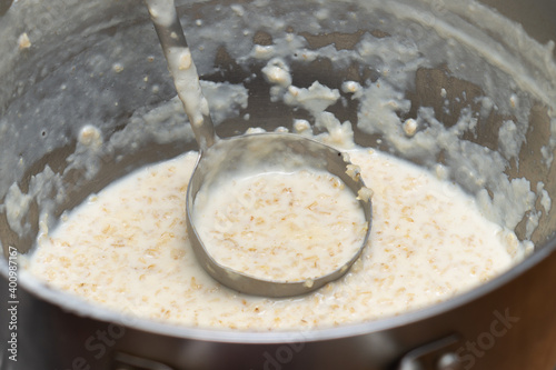 Big pan of tasty just prepared oatmeal porridge with a ladle in canteen