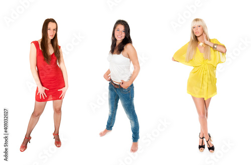 Full length portraits of three attractive young women wearing colorful clothes, isolated on white studio background