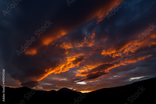Picturesque sunset on a dark cloudy sky over the silhouette of distant mountains