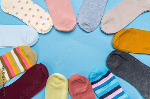Many socks are piled in a circle in blue background. View from above.
