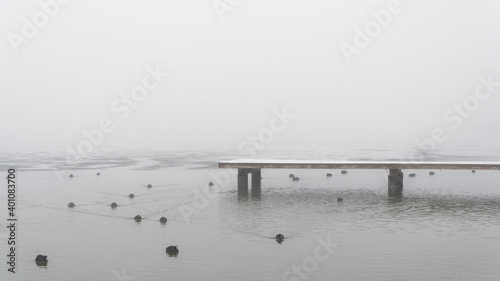 Molo na pokrytym lodem jeziorze we mgle