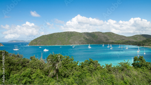 White luxury boats on the turquoise waters of St. Thomas with green trees and a mountain.