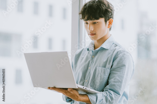 Asian businessman is using laptop to work by window