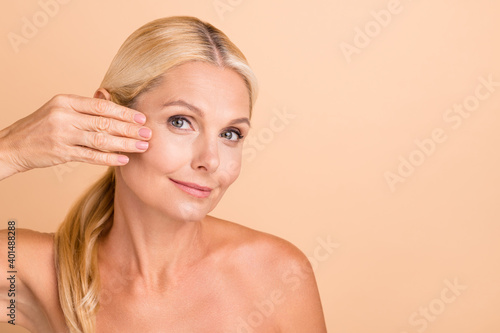 Closeup photo of natural beauty aged lady nude shoulders touch fingers cheek apply anti age uplift cream isolated beige color background