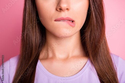 Close-up photo portrait of woman biting lower lip isolated on pastel pink colored background