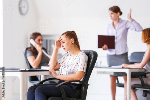 Stressed woman with headache and noisy people in office