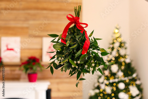 Mistletoe bunch with red bow hanging in room decorated for Christmas