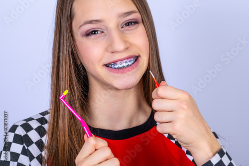 Dentist and orthodontist concept. Girl with braces cleaning teeth using brushes