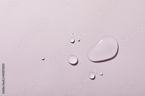 A top view closeup of multiple water drops on a light purple background
