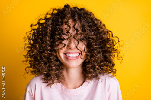 Headshot of laughing cheerful girl with curly hairstyle wearing t-shirt white toothy smile isolated on bright yellow color background