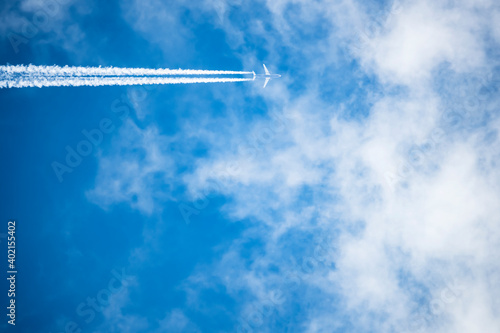Stunning view of a jet forming contrails in a blue sky. Cloudy sky with copy space.