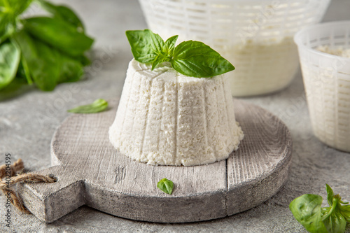 Homemade whey ricotta cheese or cottage cheese with basil ready to eat. Vegetarian healthy, nutritious diet food on a light background