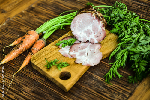 Sausage served on an oak board among vegetables from the home garden.