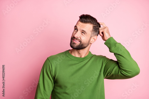 Photo portrait of unsure clueless man looking empty space wearing green jumper isolated pastel pink color background