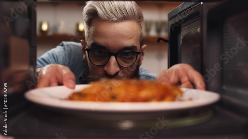 Man opening microwave oven door and taking warmed food