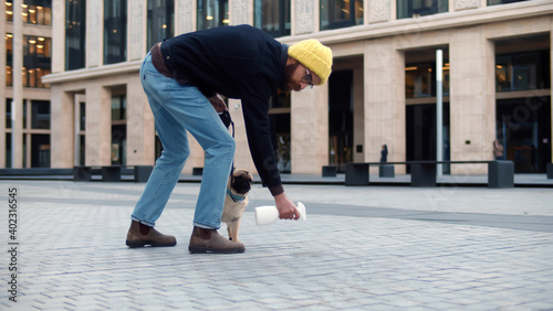 Man bending down and spraying with detergent pet pee on pavement outdoors