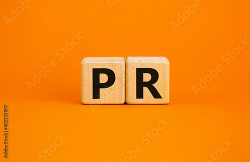 PR - public relations symbol. Wooden cubes with words 'PR, public relations' on beautiful orange background, copy space. Business and PR - public relations concept.