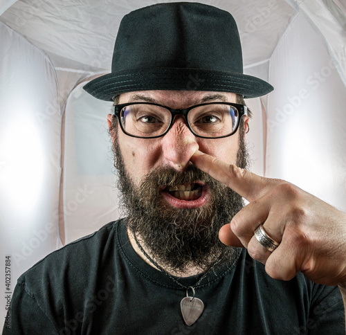 A silly looking bearded man with glasses and a black hat