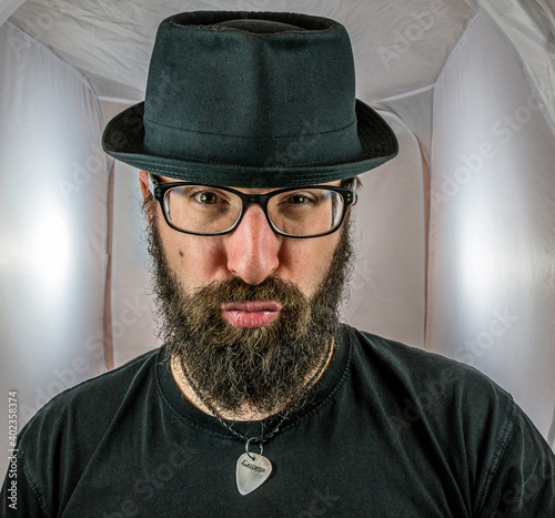 a bearded man with a duck face in a sexy mood with black glasses and hat