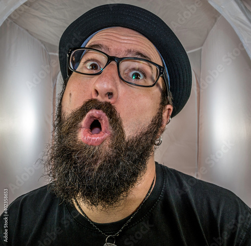 A surprised looking bearded man with black hat and glasses