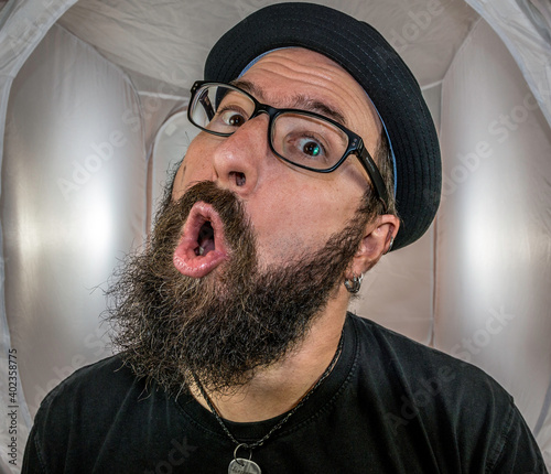 A surprised looking bearded man with black hat and glasses