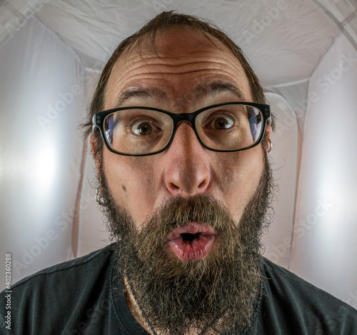A surprised looking bearded man with glasses