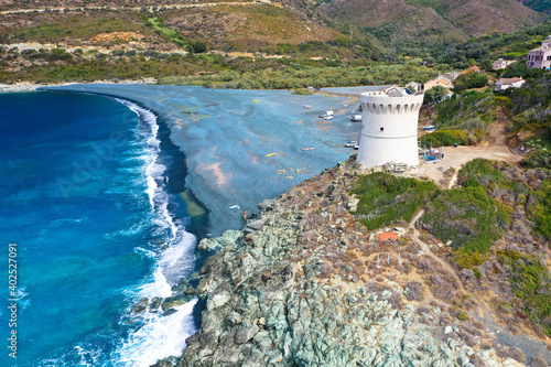 Drone aerial view of Plage de Nonza with the Genoese tower, the long black beach at the foot of the cliffs on which the small town of Nonza stands, the famous village on the coast of Cap Corse