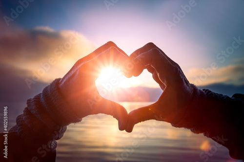 Herz aus Händen mit Sonnenlicht am See