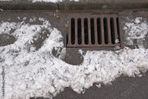 1 - Melting snow flows into an iron kerbside surface drain.