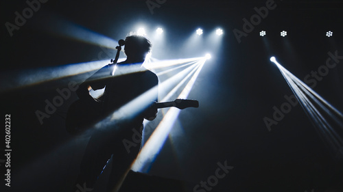 Silhouette of guitar player performinf on concert stage. Dark background, smoke, concert spotlights