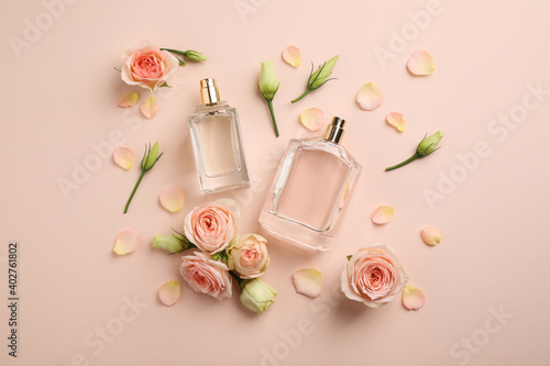 Flat lay composition with different perfume bottles and fresh flowers on beige background