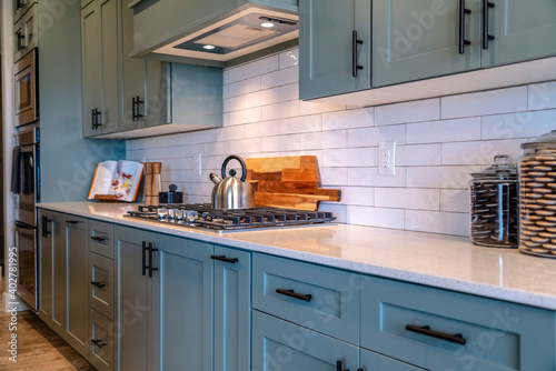 Cooking area of home with cabinets and exhaust hood over cooktop and countertop