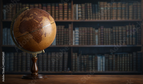 Old geographic globe in the cabinet against the background of bookselfs.Science, education, travel, vintage background. History and geography team.