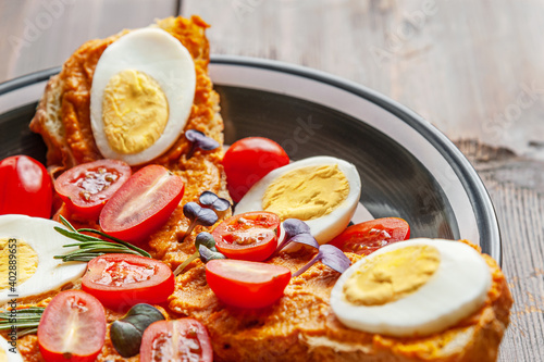 bruschettas of dietary bread with vegetable puree and boiled eggs decorated with cherry tomatoes and young herbs