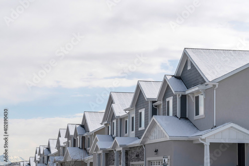 Townhouses with snowy gable roofs in winter on a scenic suburbs community.
