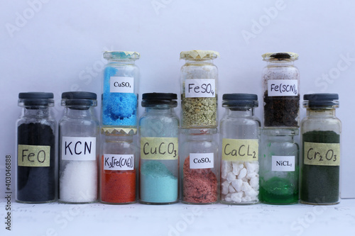 Glass jars with different colored inorganic reagents, with chemical formulas.