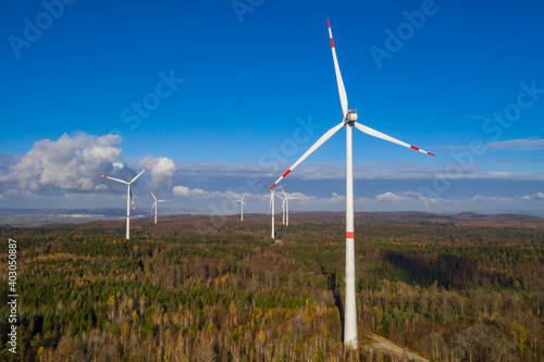 wind farm in a colorful autumn forest with blue sky