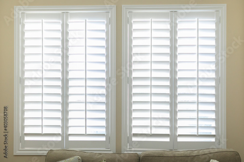 A set of open white plantation shutters in a light butter yelllow room