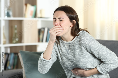 Woman with a stomach ache about to vomit at home