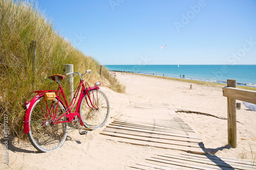 Vieux vélo rouge en bord de mer le long d'une plage en France.